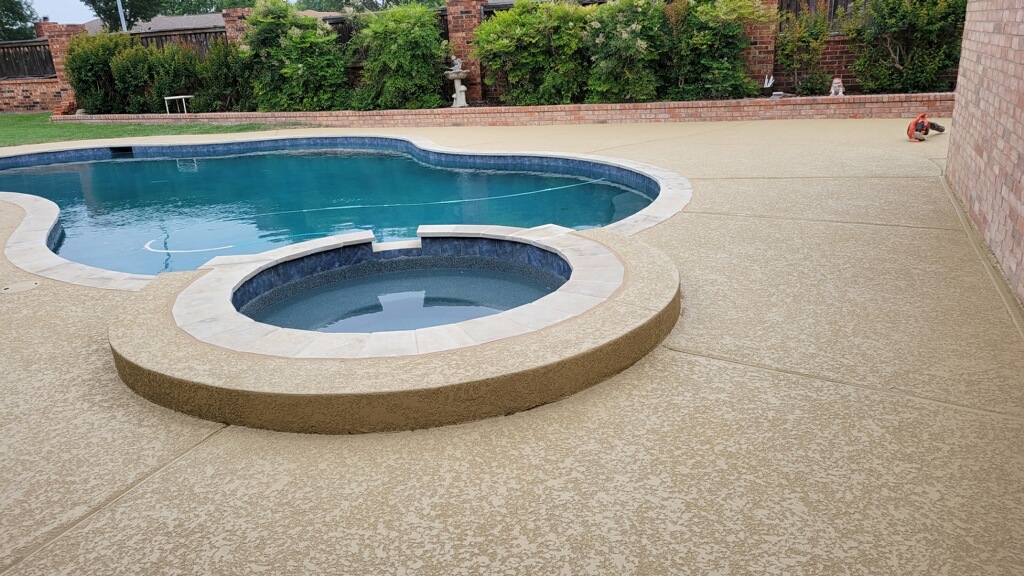 Textured concrete pool deck surrounding a freeform pool and raised spa