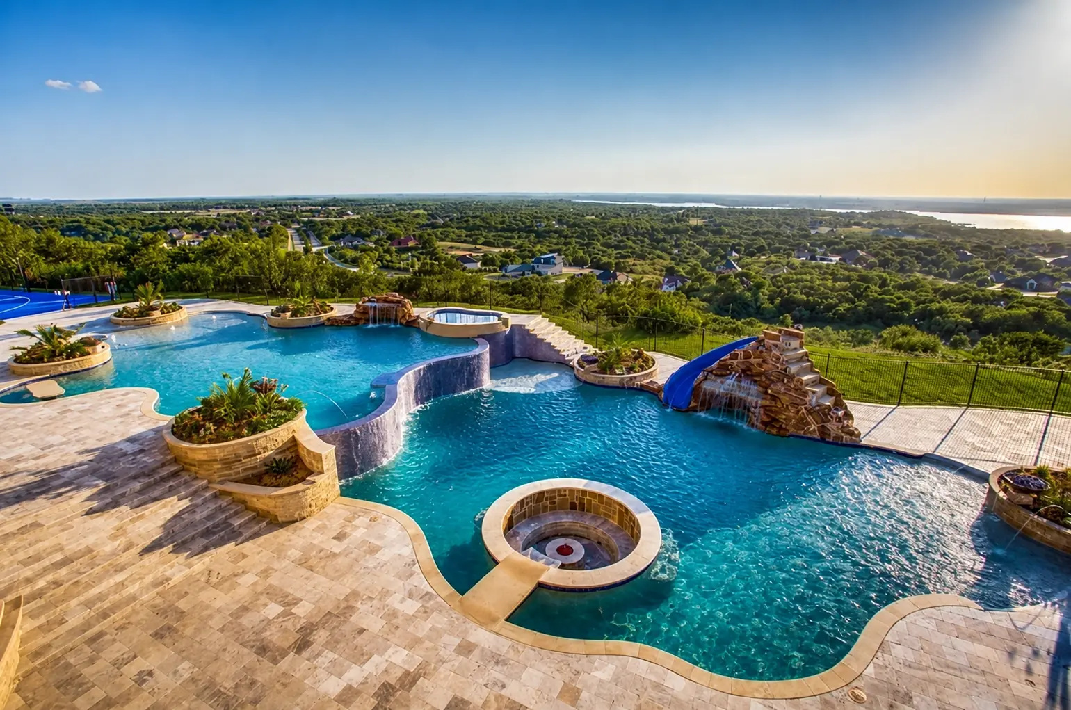 Large custom hillside swimming pool with waterfalls, spa, and waterslide by King Pools