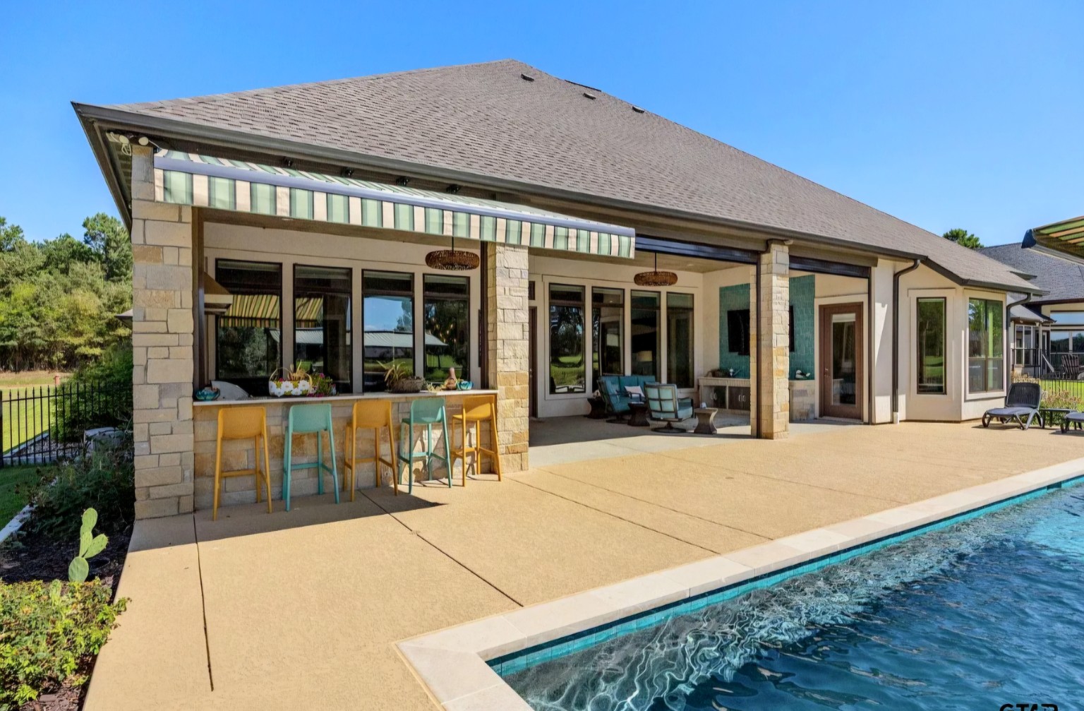 The view along the pool reveals the connection between the water, custom decking, and covered entertaining space.