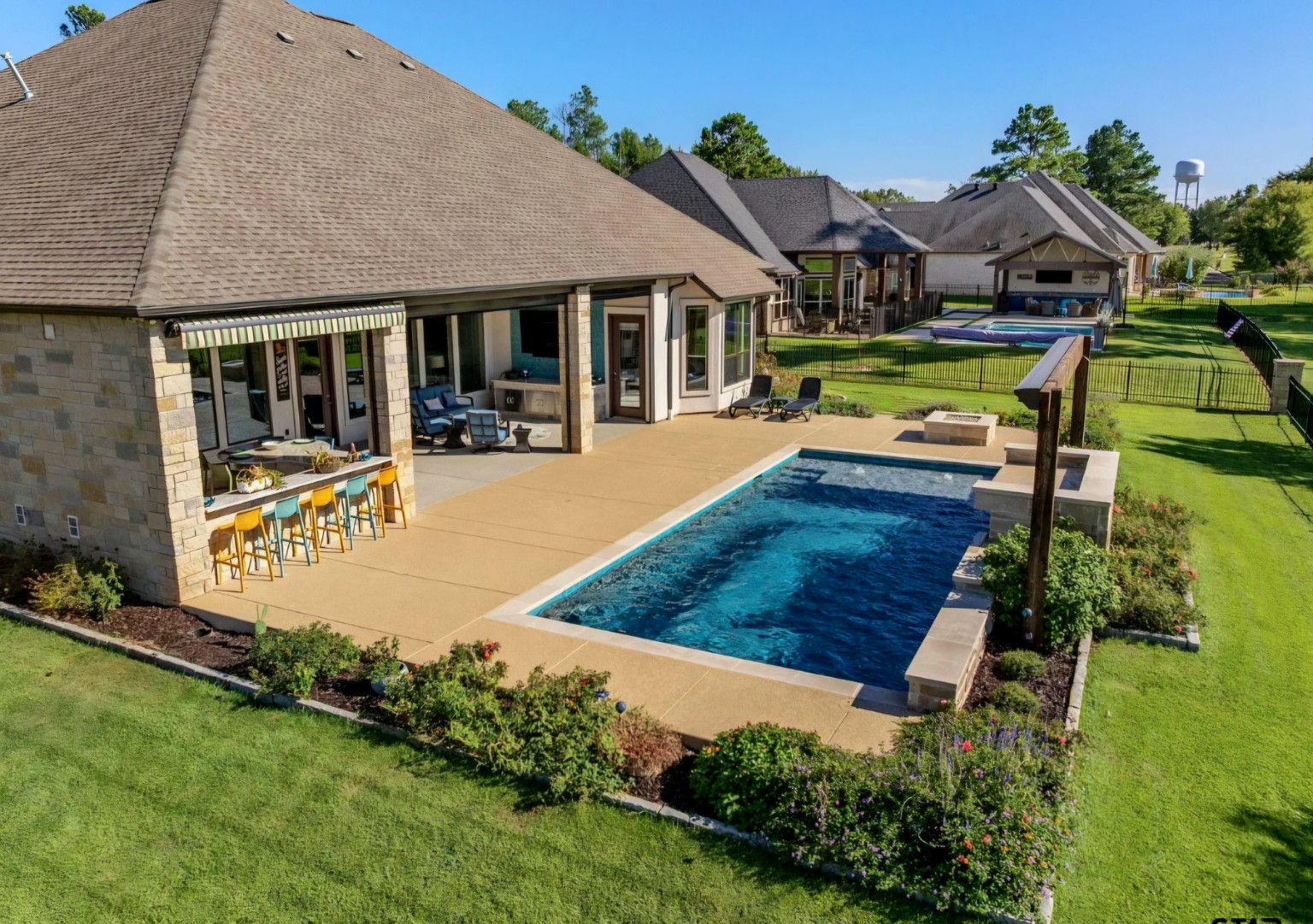 The completed backyard brings the larger swimming pool, outdoor kitchen, covered patio, and surrounding grounds together in one cohesive design.