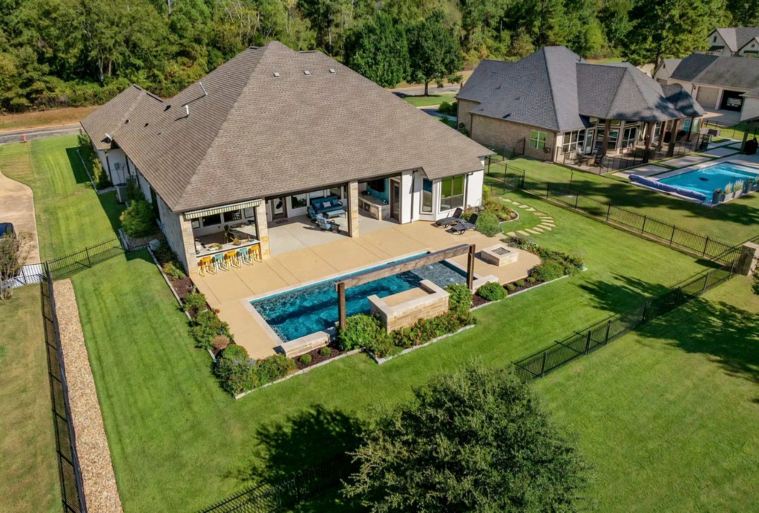 An aerial overview of the completed transformation, from the new pool to the outdoor living spaces and surrounding yard.