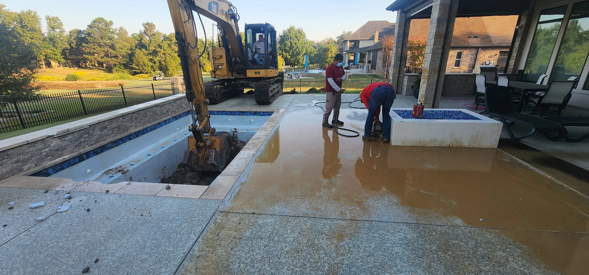 Excavator removing the original pool beside the existing deck