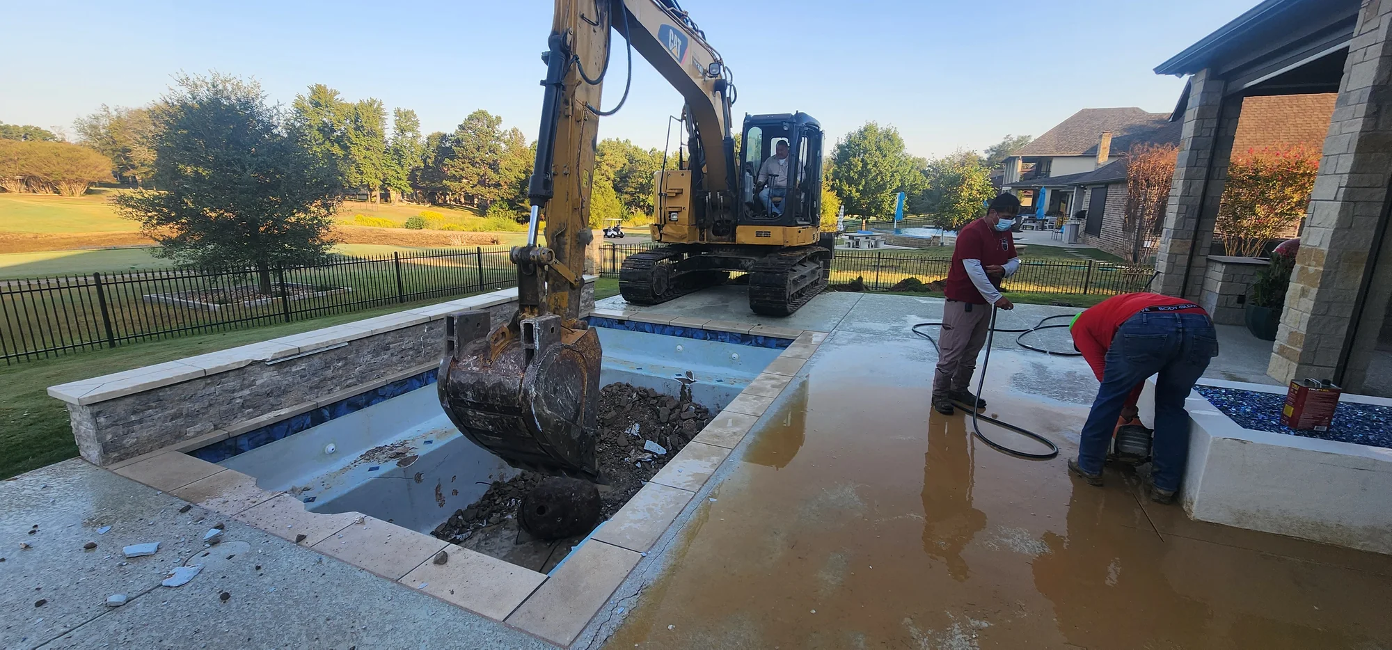 Excavator lifting debris from the original pool