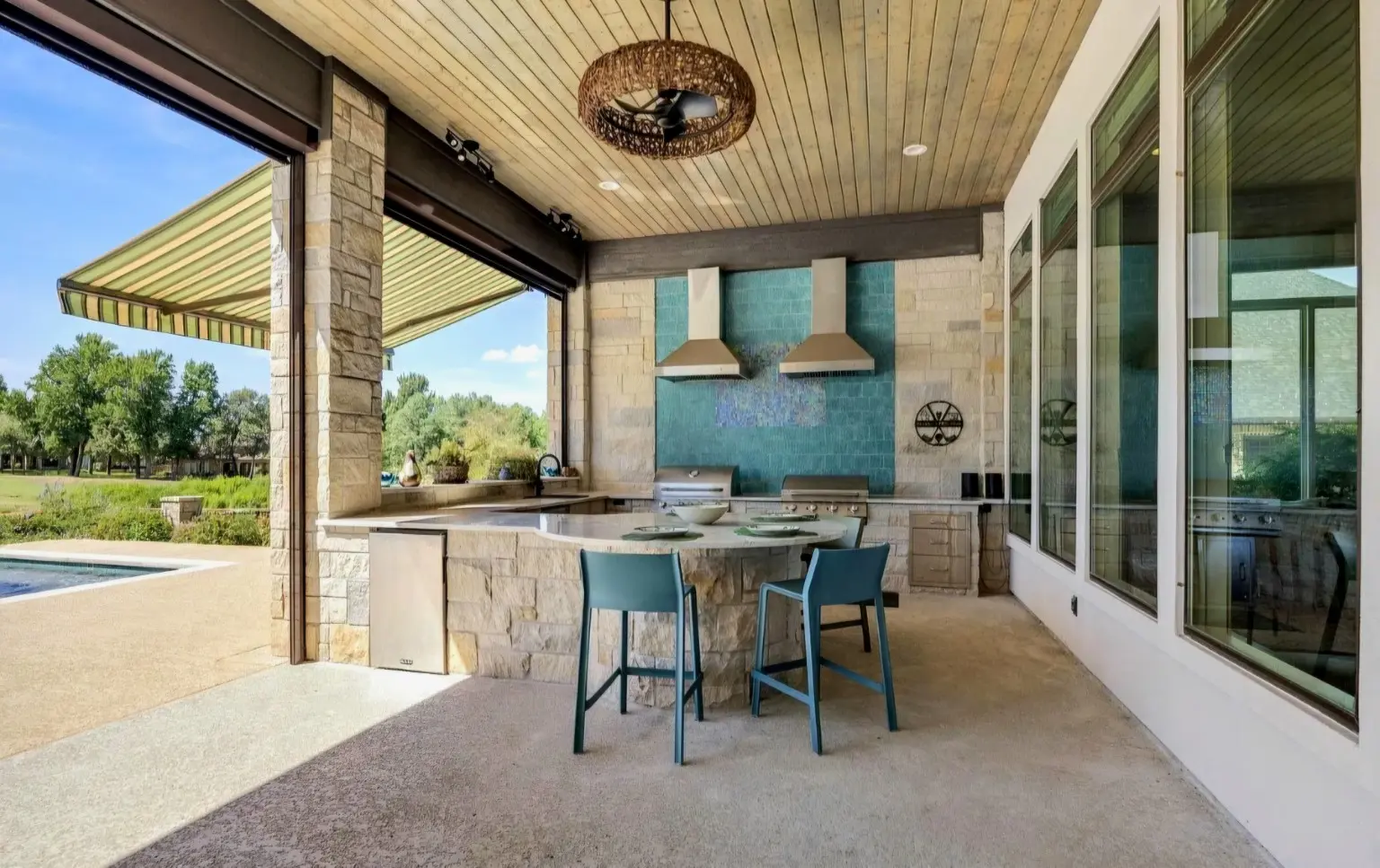 Finished stone outdoor kitchen and bar beside the pool